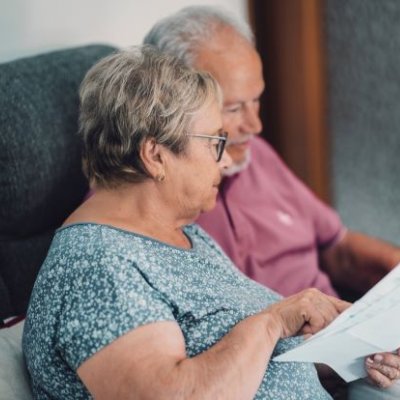 An elderly man and woman looking over a sheet of paper 